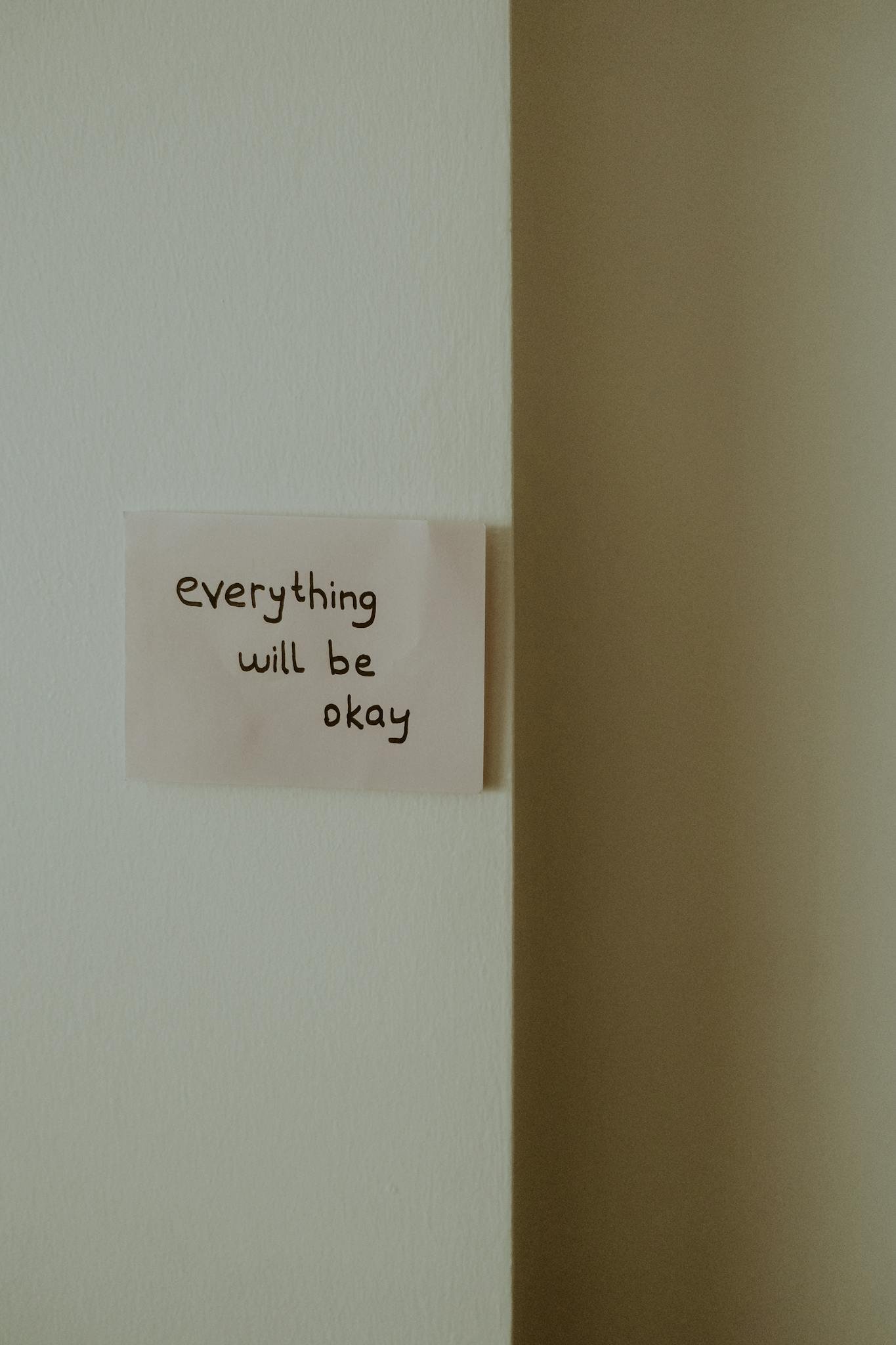 A simple note with 'everything will be okay' message on a minimalist wall.